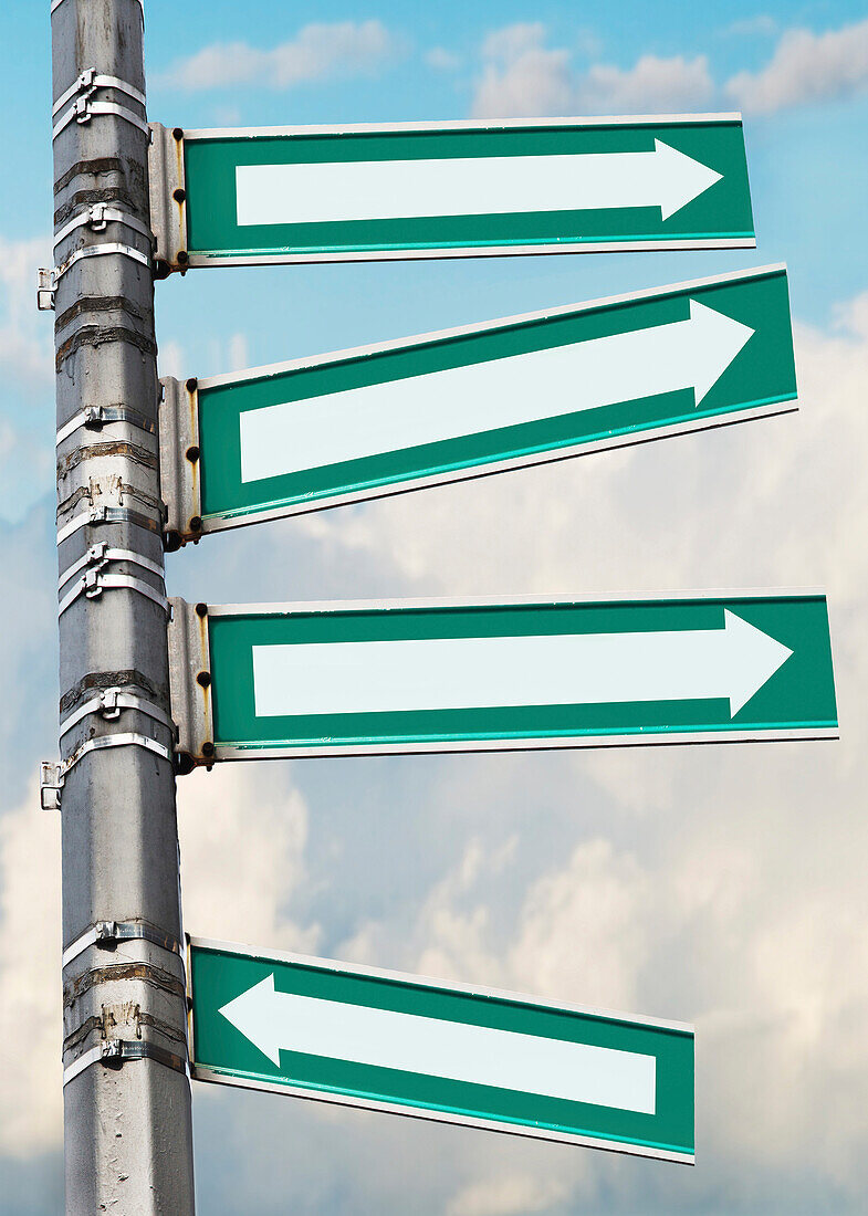 Arrow signs on a pole, showing different directions against sky