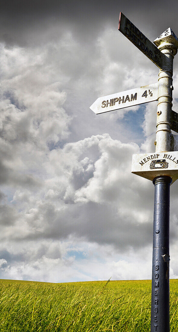 Old signpost with stormy sky and grassy field in the countryside in Sommerset, England