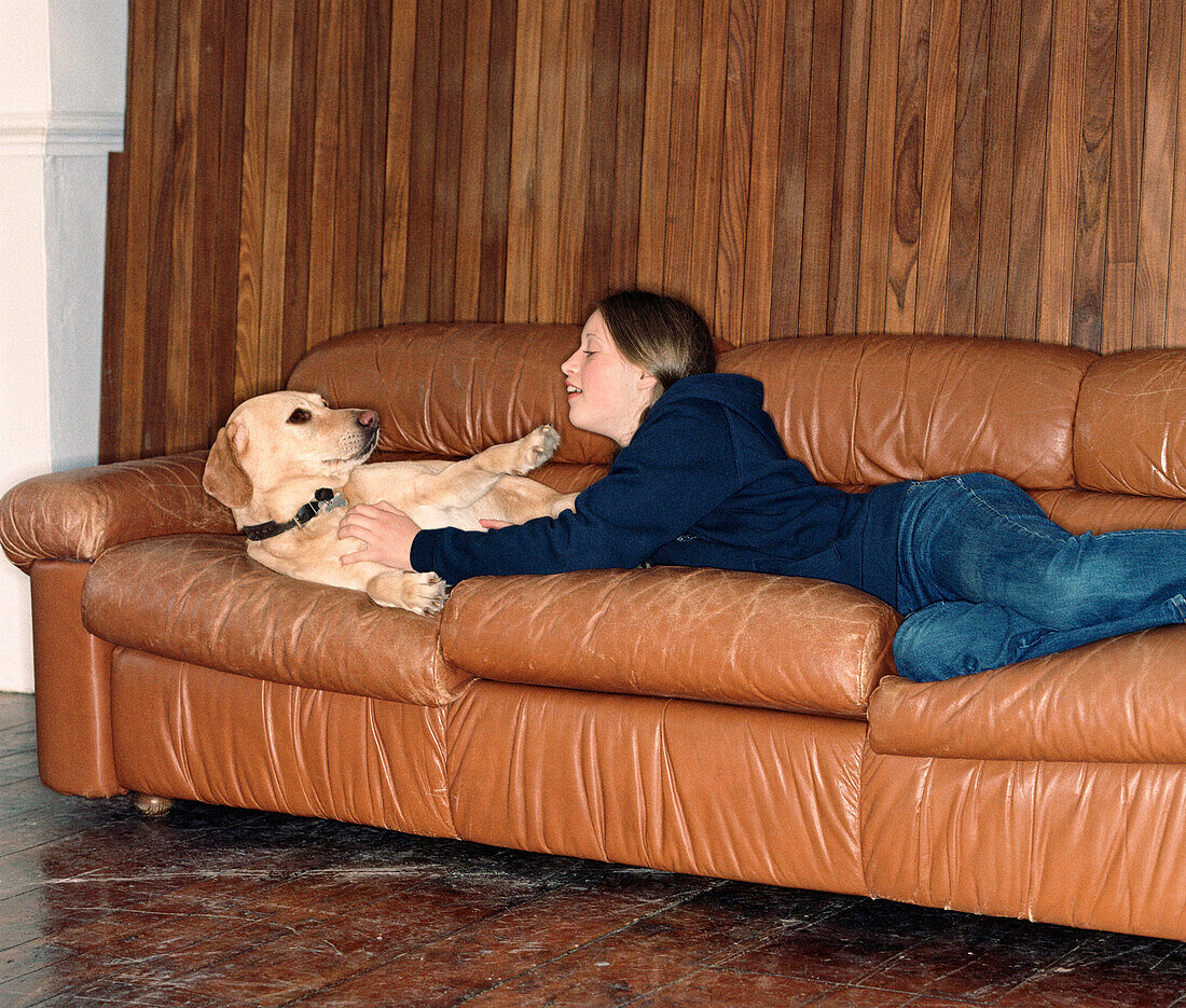 Teenager-Mädchen mit Hund auf Sofa liegend