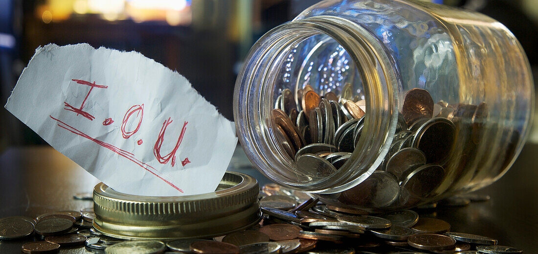Einmachglas mit Münzen und Schuldschein (IOU Note)