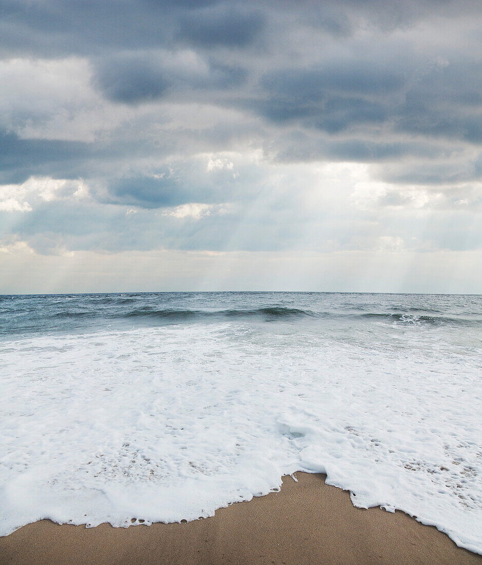 Wellen am Strand mit Sonnenstrahlen durch Wolken, Point Pleasant, New Jersey, USA