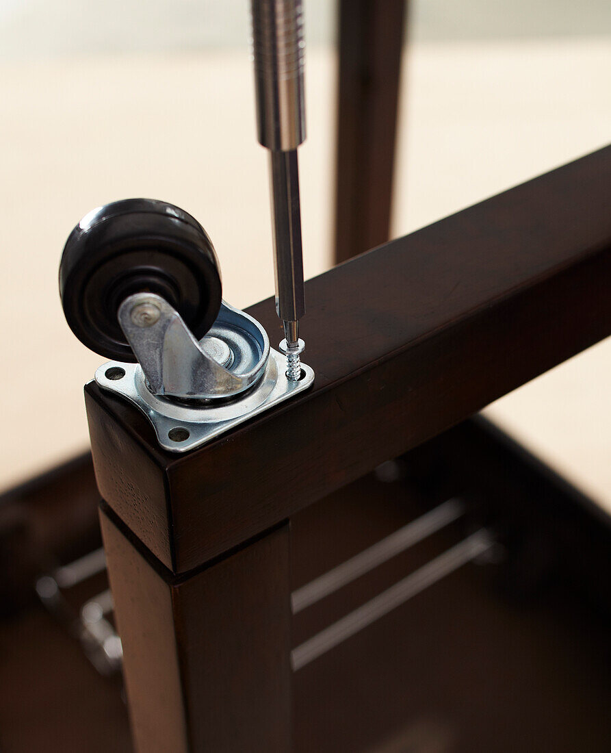 Close-up of Screwdriver Attaching Caster Wheel to Table