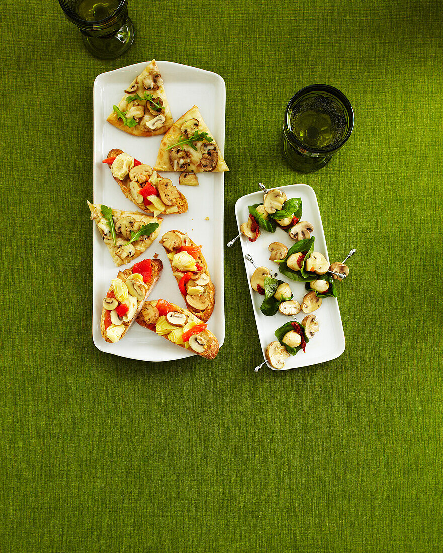 Overhead View of Mushroom Appetizers on Trays with Drinking Glasses on Green Background in Studio