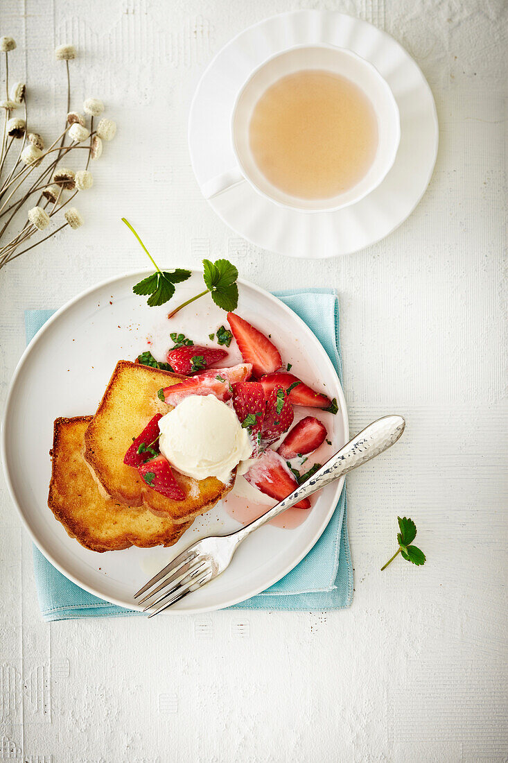 Draufsicht auf Erdbeeren auf French Toast mit Eiscreme und Tasse Tee, Studioaufnahme