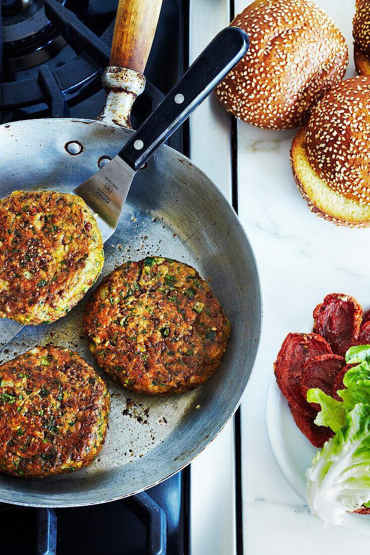 Chickpea falafel burgers in frying pan on stove, studio shot