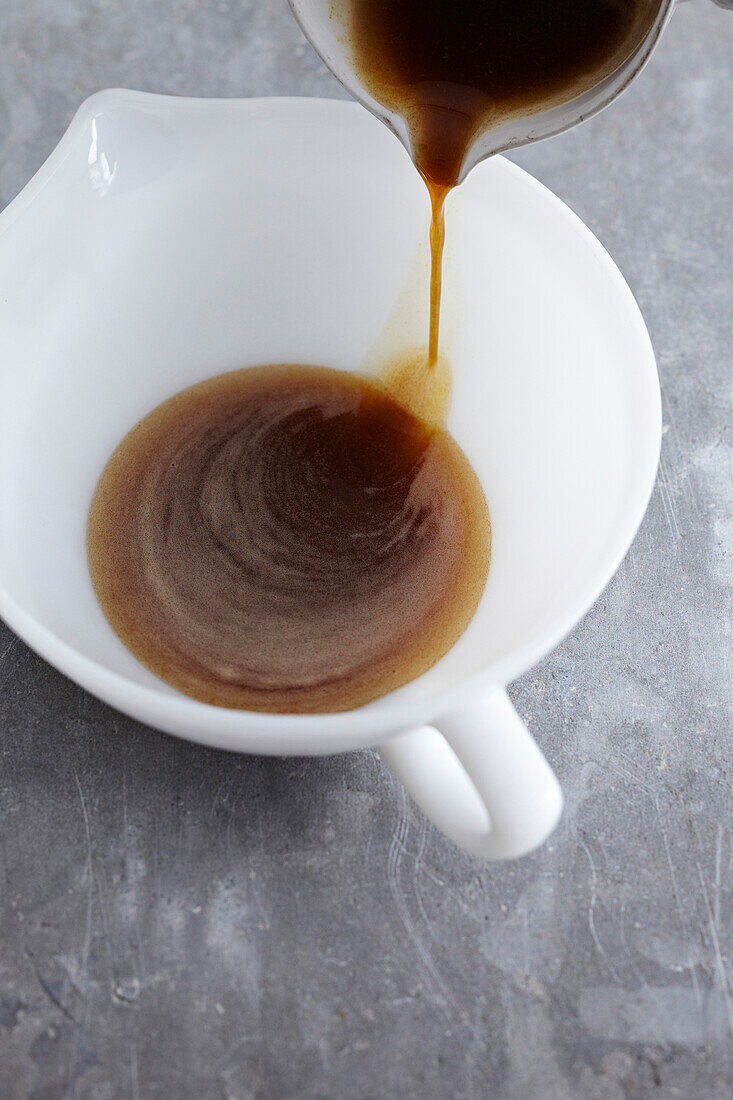 Close-up of liquified brown butter being poured into creamer, studio shot