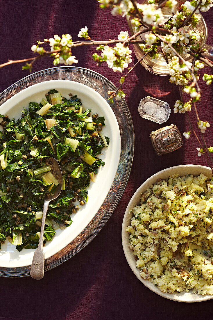 Swiss chard with capers and smashed potatoes on platters, studsio shot