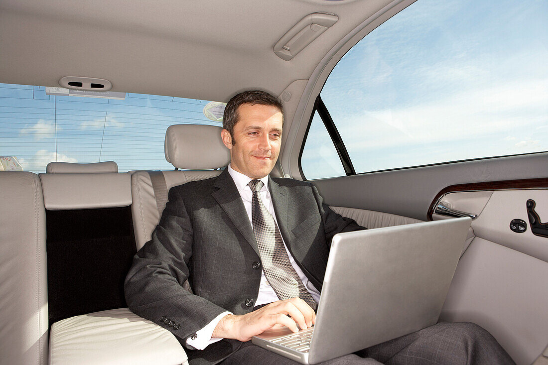 Geschäftsmann mit Laptop-Computer im Auto