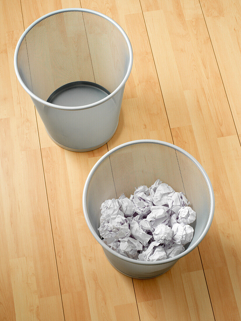 Overhead view of empty and used waste baskets on wooden floor, studio shot