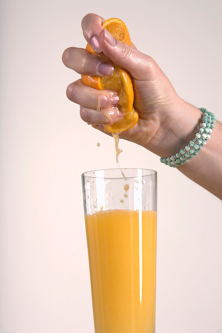Frau presst Orange aus, macht Orangensaft