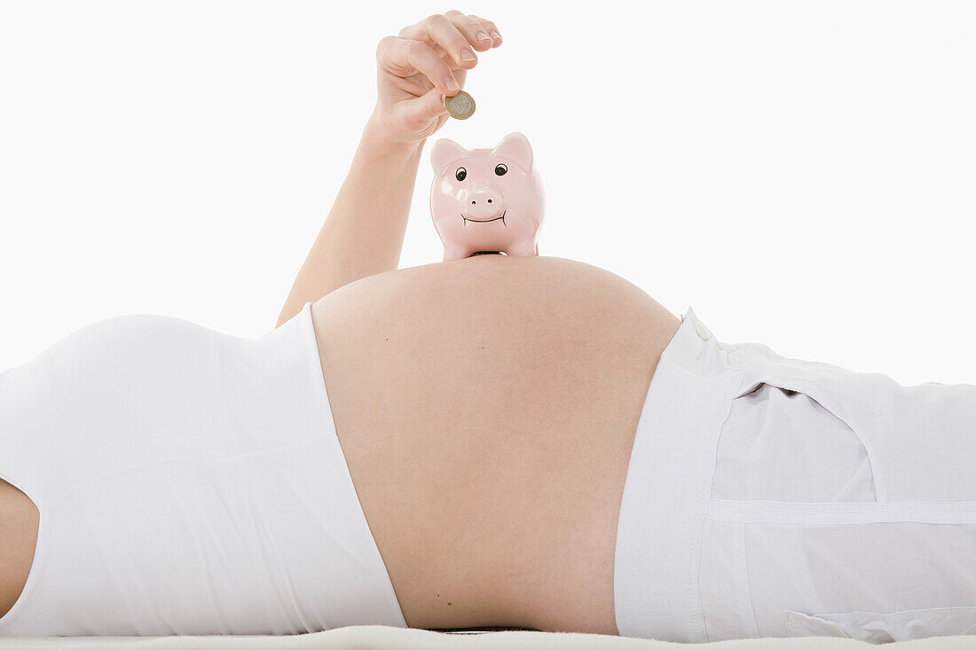 Sparschwein auf dem Bauch einer schwangeren Frau