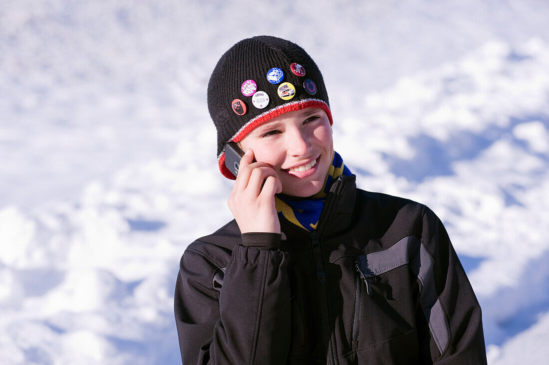 Junge telefoniert im Winter draußen mit dem Handy, Salzburger Land, Österreich