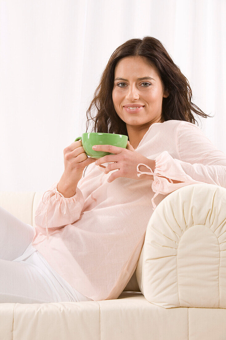 Frau auf Sofa mit Kaffeetasse