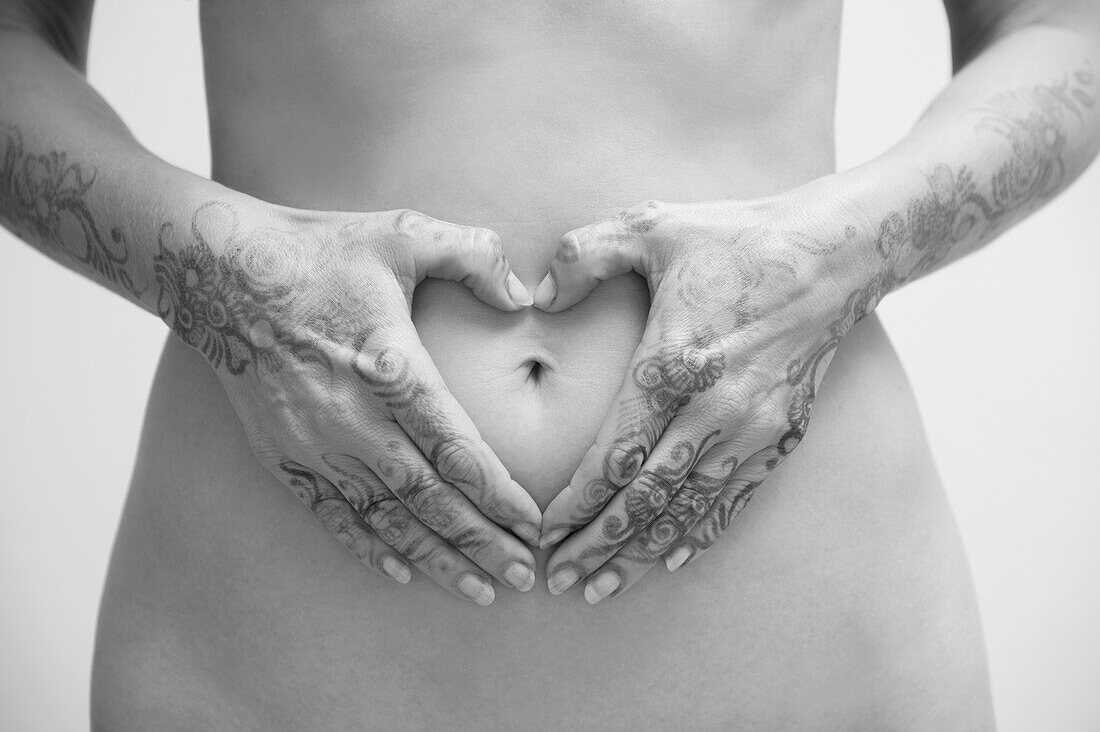 Close-up of Woman with Henna on Hands, Hands in Heart-shape around Belly Button, Studio Shot