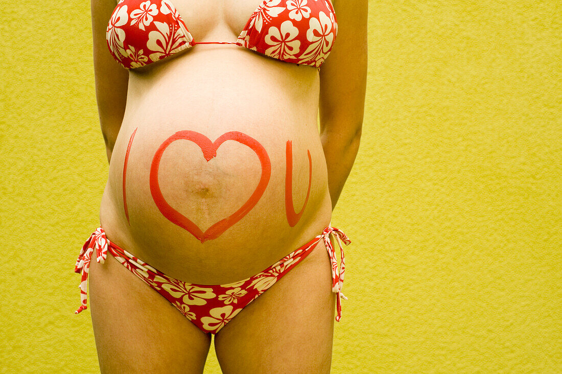 Schwangere Frau mit "Ich liebe dich" auf den Bauch gemalt