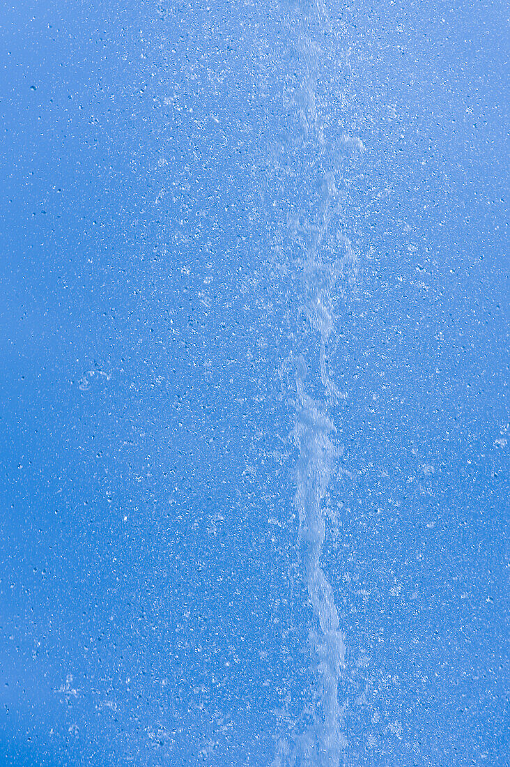 Wassertropfen aus Wasserfontäne vor blauem Himmel