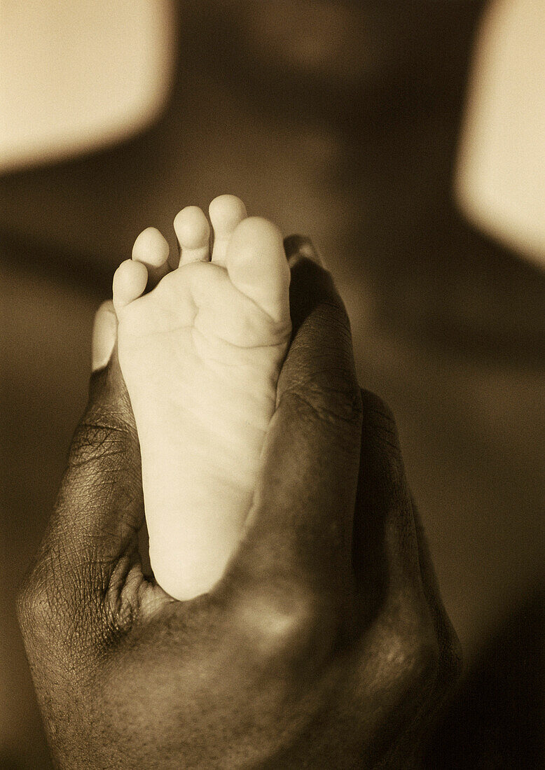 Nahaufnahme eines Mannes, der den Fuß eines Babys hält