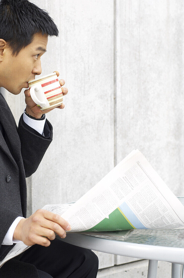 Geschäftsmann trinkt Kaffee und hält eine Zeitung