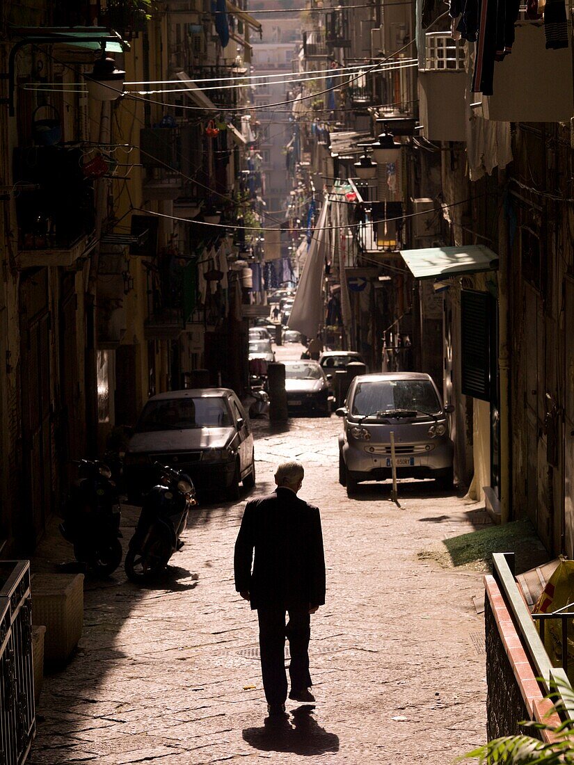 Man Walking On Street Of Historic Old Town, Rear View; Naples, Italy