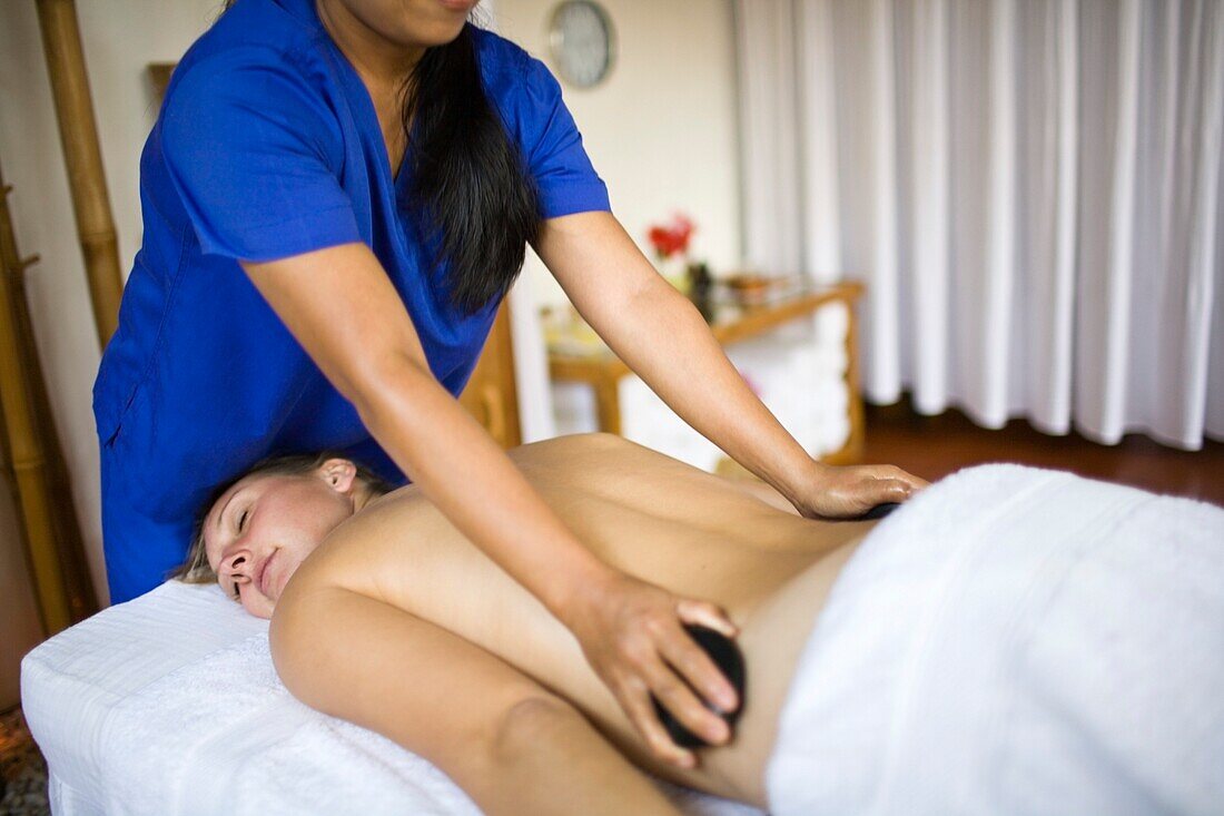 Woman Getting Hot Stone Massage By Masseuse; Puerto Gallera, Mindoro Island, Philippines
