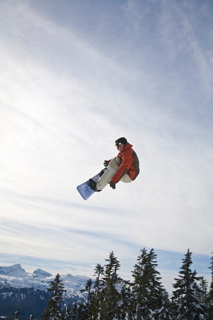 Mann beim Snowboarden, Springen mitten in der Luft; Vancouver Island Ranges, British Columbia, Kanada