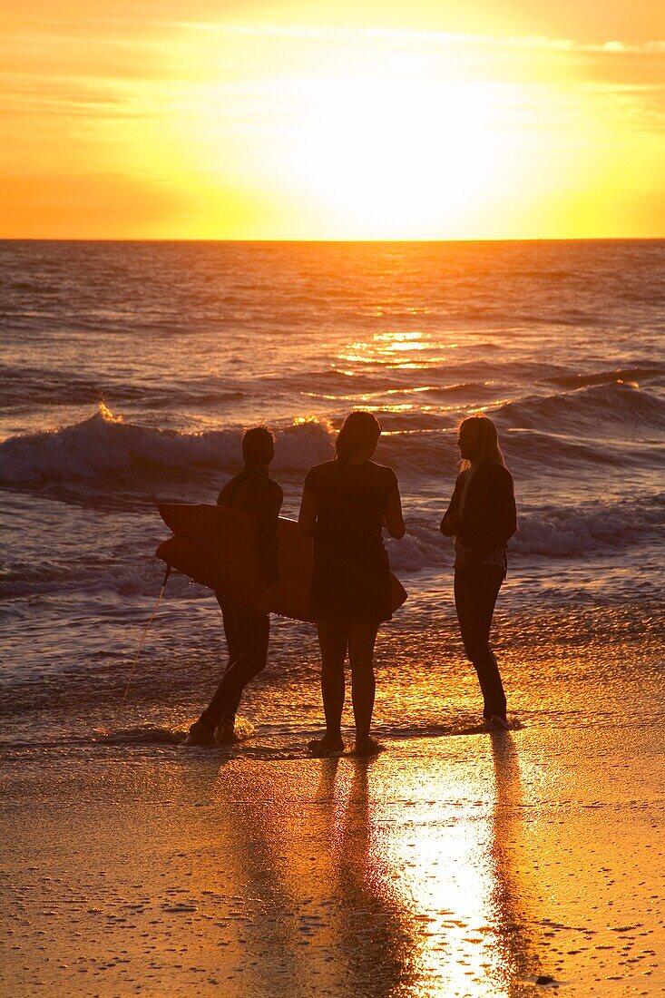 Drei Surfer stehen bei Sonnenuntergang am Strand von San Clemente Beach; San Clemente, Orange County, Kalifornien, USA