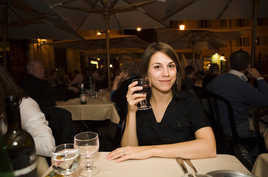 Frau lächelt mit einem Glas Wein, im Freien; Rom, Italien