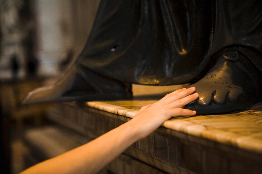 Frau berührt den Fuß einer Skulptur im Petersdom; Vatikanstadt, Rom, Italien