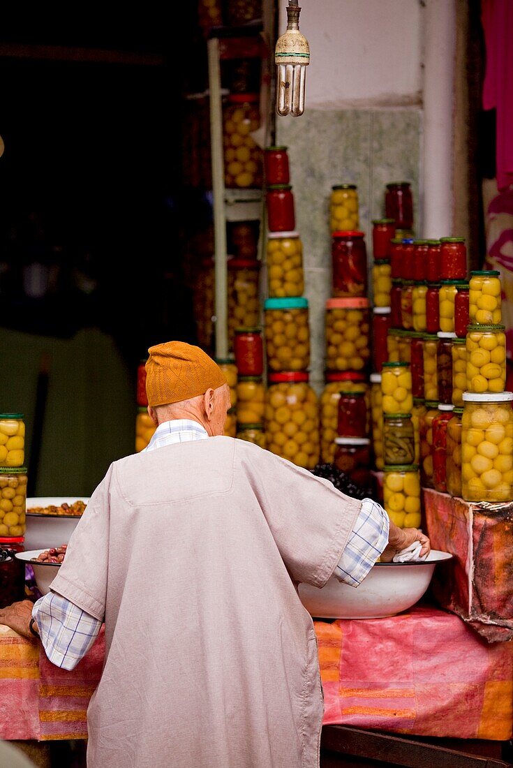 Ein Mann legt konservierte Zitronen und Oliven auf dem Olivensouq aus; Marrakesch, Marokko