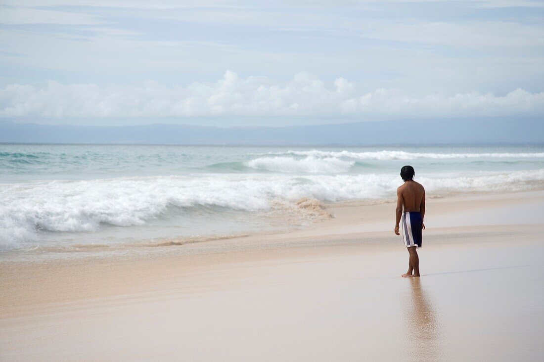 Teenager Looking At Surf On Beach