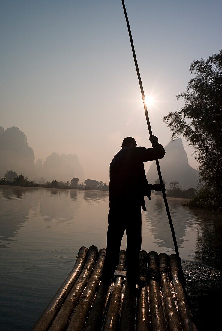 Mann auf Floß in Berggebiet; Yulong-Fluss, Yangshuo, China