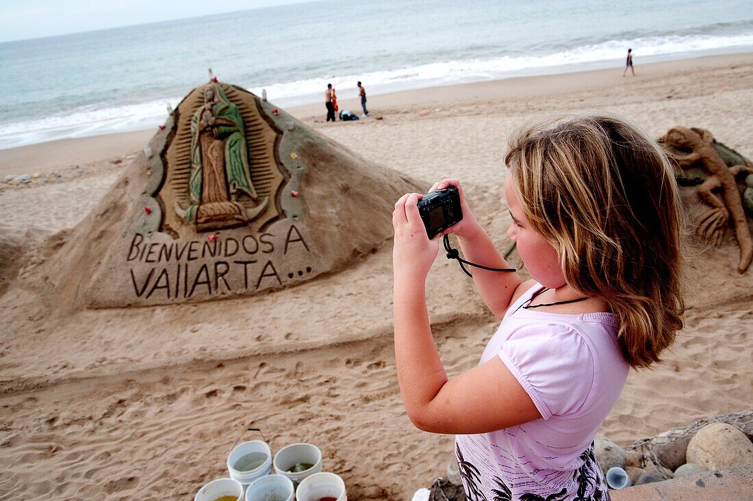 Malecon, Puerto Vallarta, Mexiko; Junges Mädchen, das eine Sandskulptur fotografiert