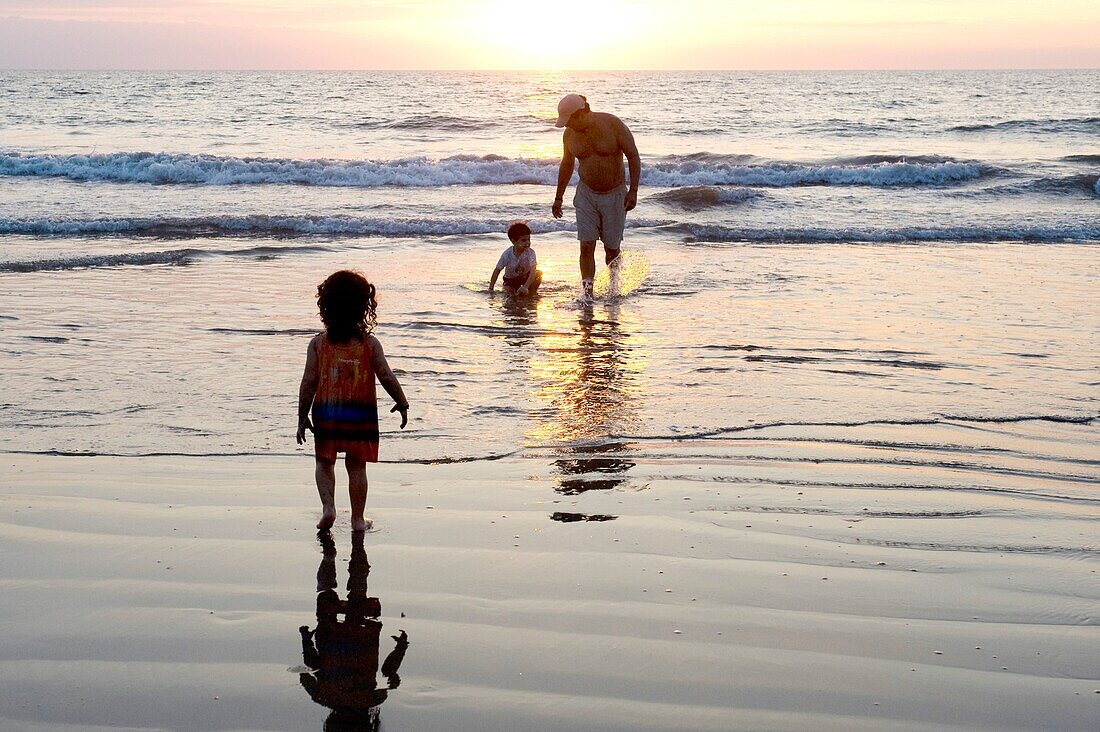 Puerto Vallarta, Mexiko; Vater am Strand mit Kindern bei Sonnenuntergang