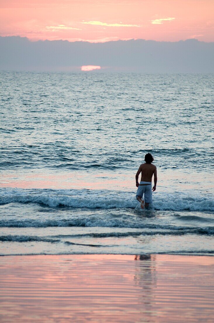Puerto Vallarta, Mexico; Young Man Wading Into Ocean At Sunset