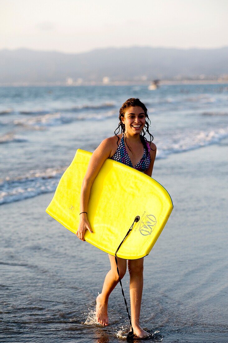 Woman On Beach Carrying Bodyboard