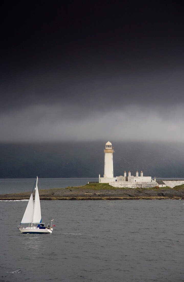Sailboat Near A Shore With A Lighthouse; Eilean Musdile In The Firth Of Lorn,Scotland