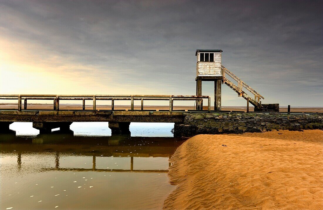 A Beach Shoreline With A Lookout Tower And A Bridge; Northumberland,England