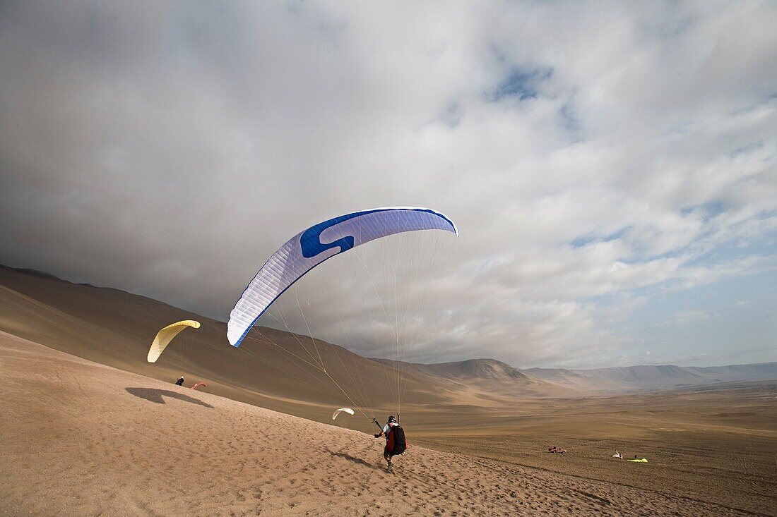 Two People Parasailing And Landing In The Desert; Iquique,Chile