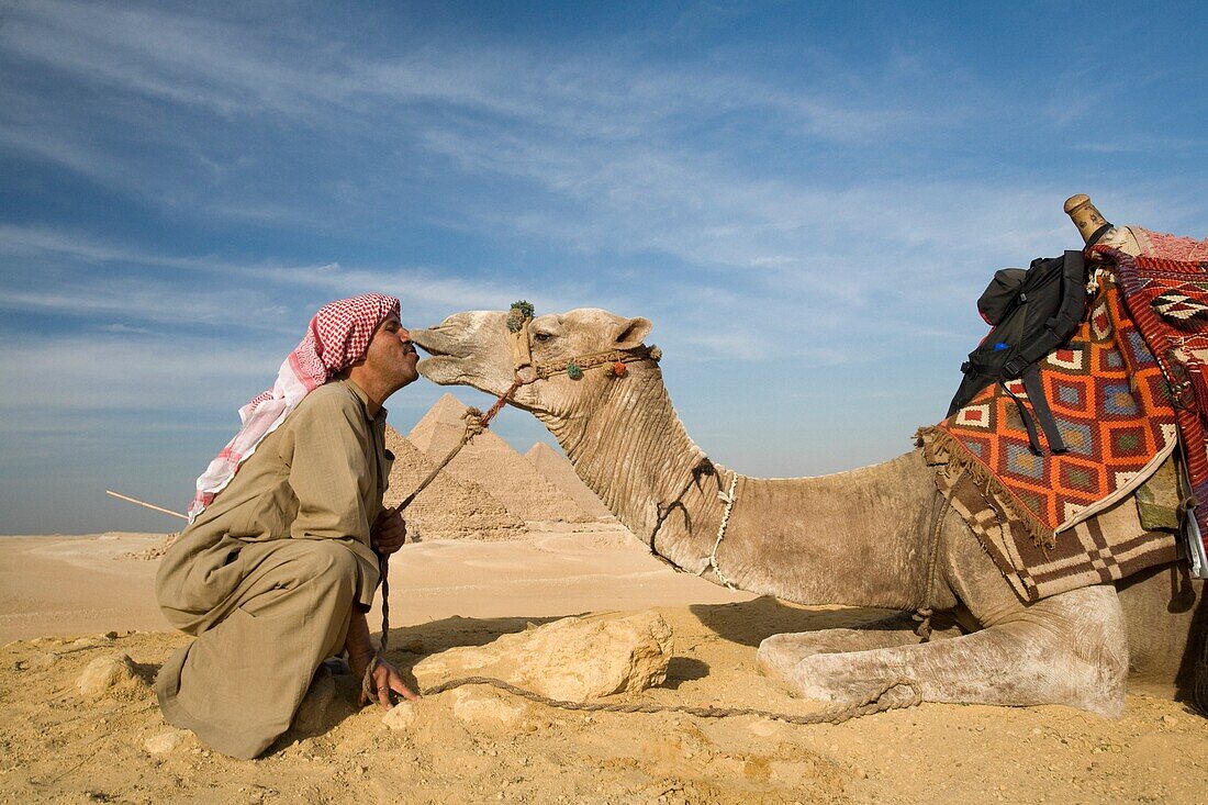 Ein Mann und ein Kamel mit den Pyramiden im Hintergrund