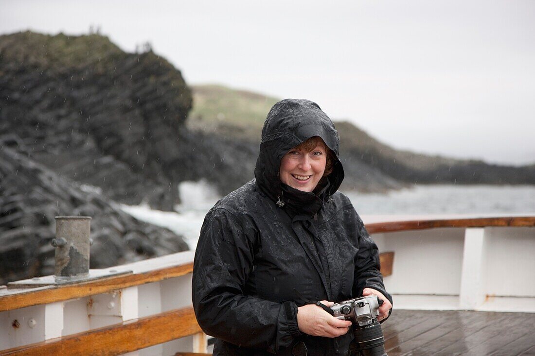 Frau im Regen, die eine Kamera hält; Insel Arran, Schottland