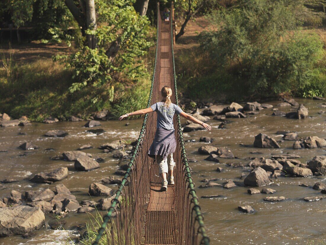 Frau geht auf Brücke; Kenia, Afrika