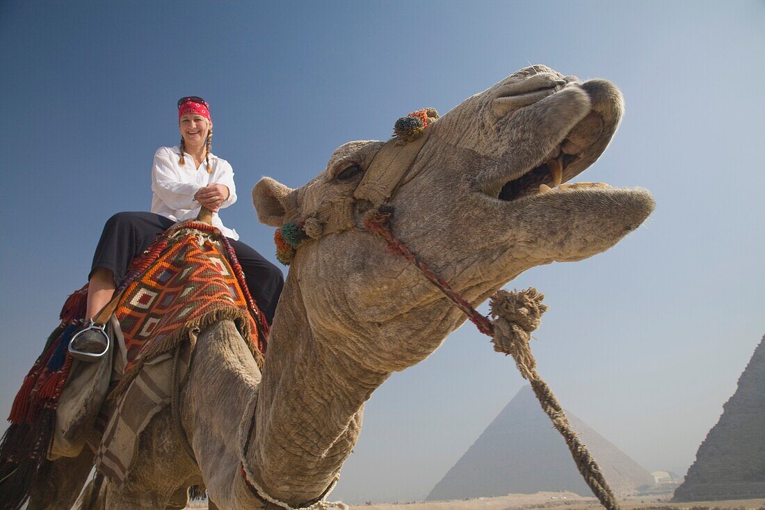 Young Woman Tourist On A Camel At The Pyramids Of Giza, Cairo, Egypt