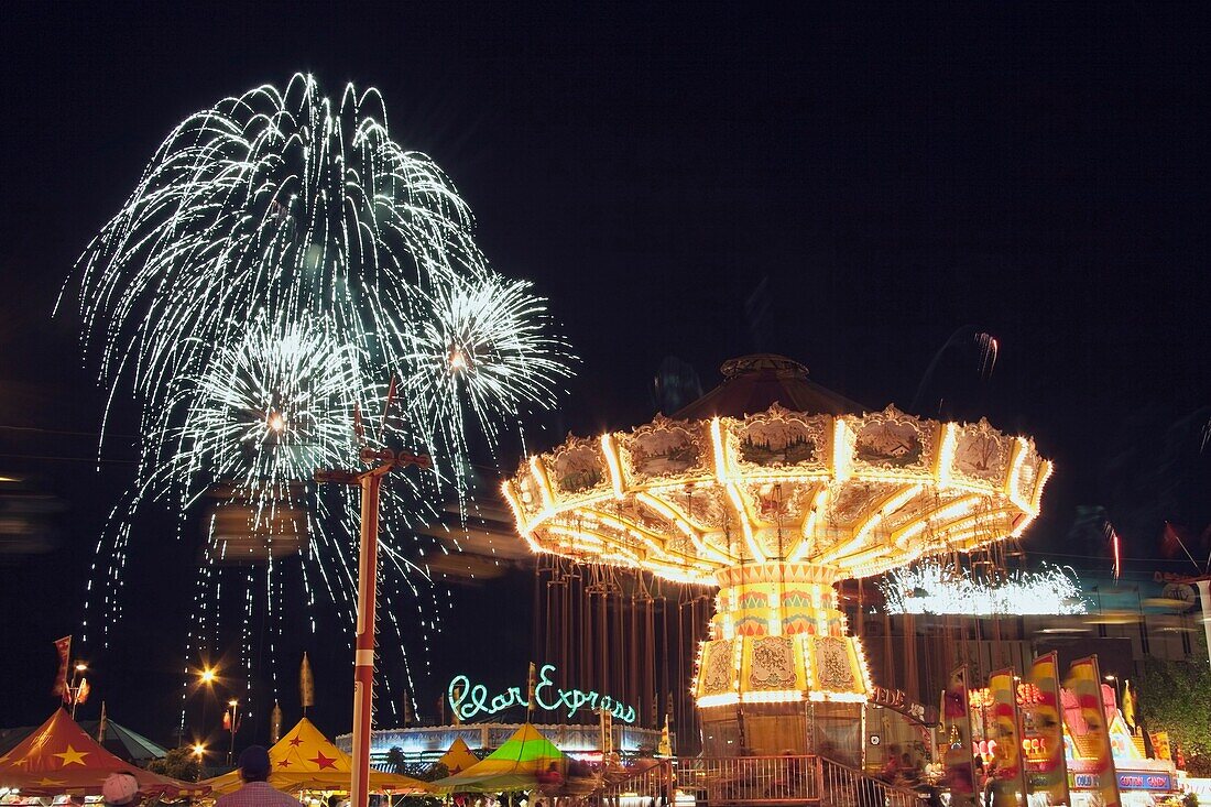 Calgary, Alberta, Kanada; Mittlere Fahrgeschäfte bei Nacht mit Feuerwerk bei der Calgary Stampede