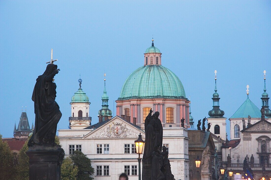 Statues On Charles Bridge With A Church In The Background; Prague, Czech Republic