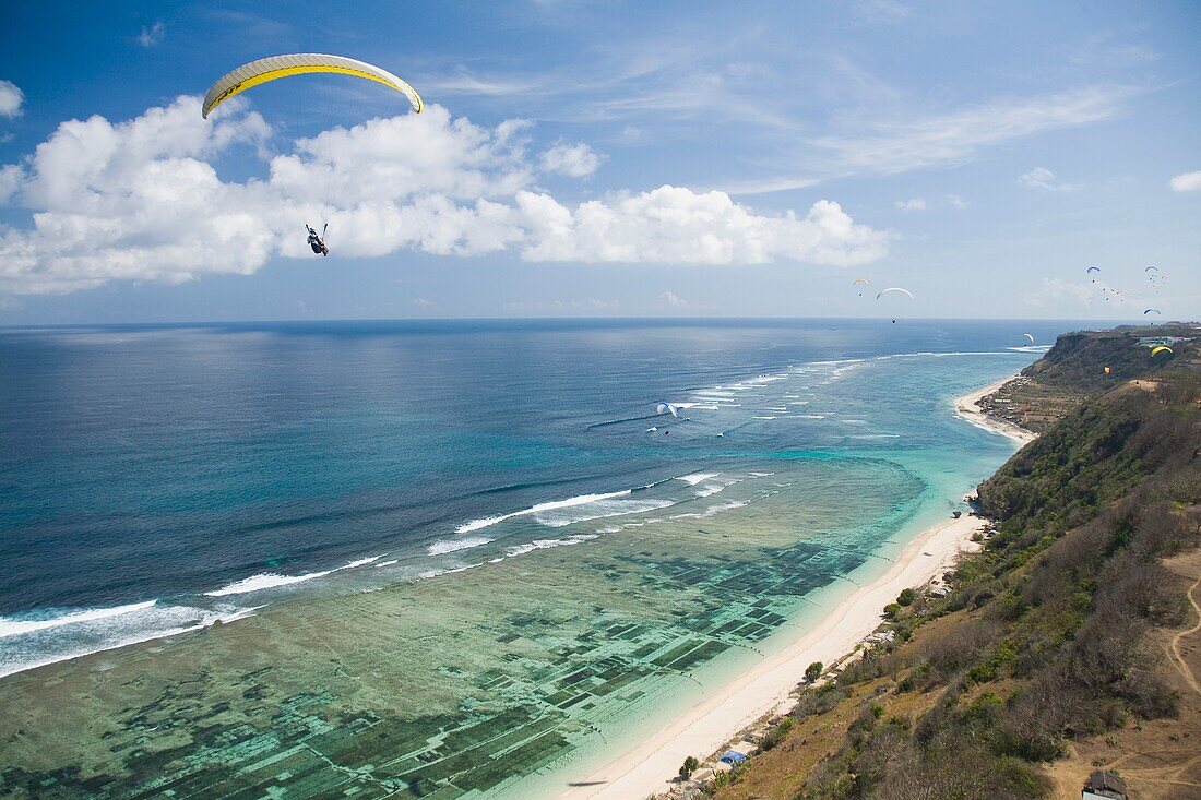 Ein Gleitschirmflieger schwebt frei über die Klippen und Strände der Bukit-Halbinsel auf Bali, Indonesien