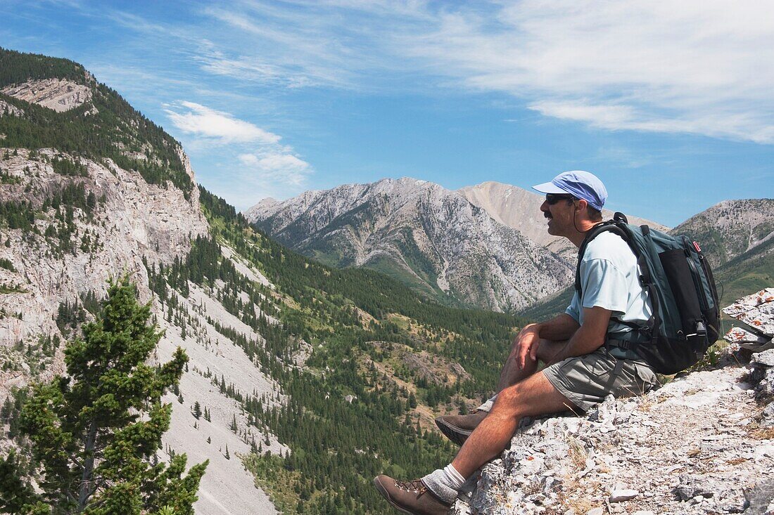 Crowsnest Pass, Alberta, Kanada; Ein männlicher Wanderer sitzt auf einem Grat und schaut auf den Turtle Mountain