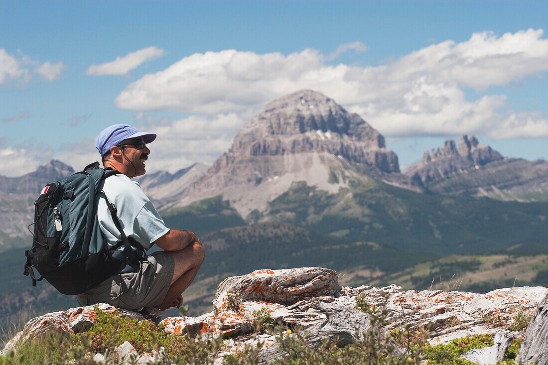 Crowsnest Pass, Alberta, Canada; A Male Hiker Sits On A Ridge Looking At The View