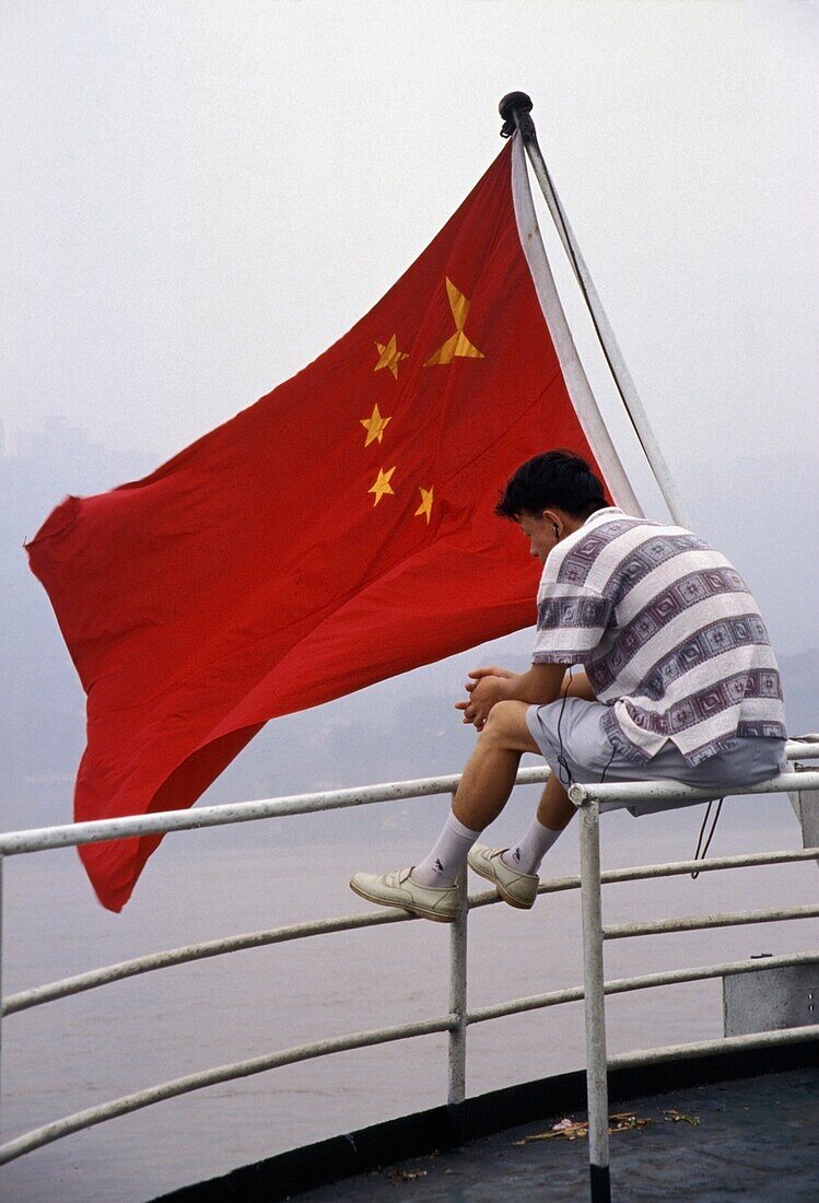 Mann mit chinesischer Flagge auf einem Boot auf dem Yangzi-Fluss