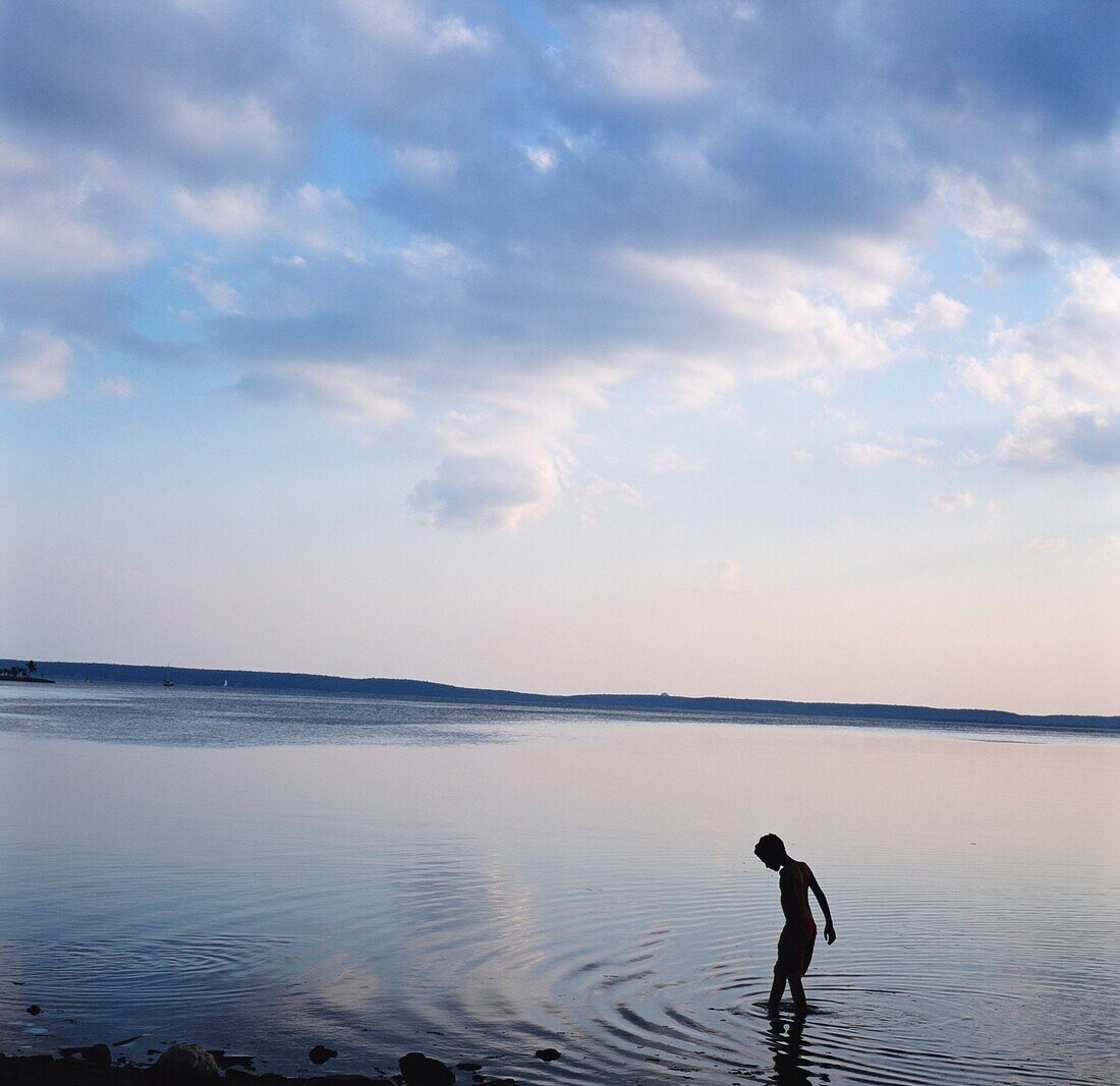 Boy In Silhouette Wading In Ocean