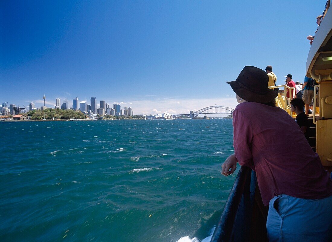 Woman Leaning On Railing On A Ferry Passing Sydney City Centre